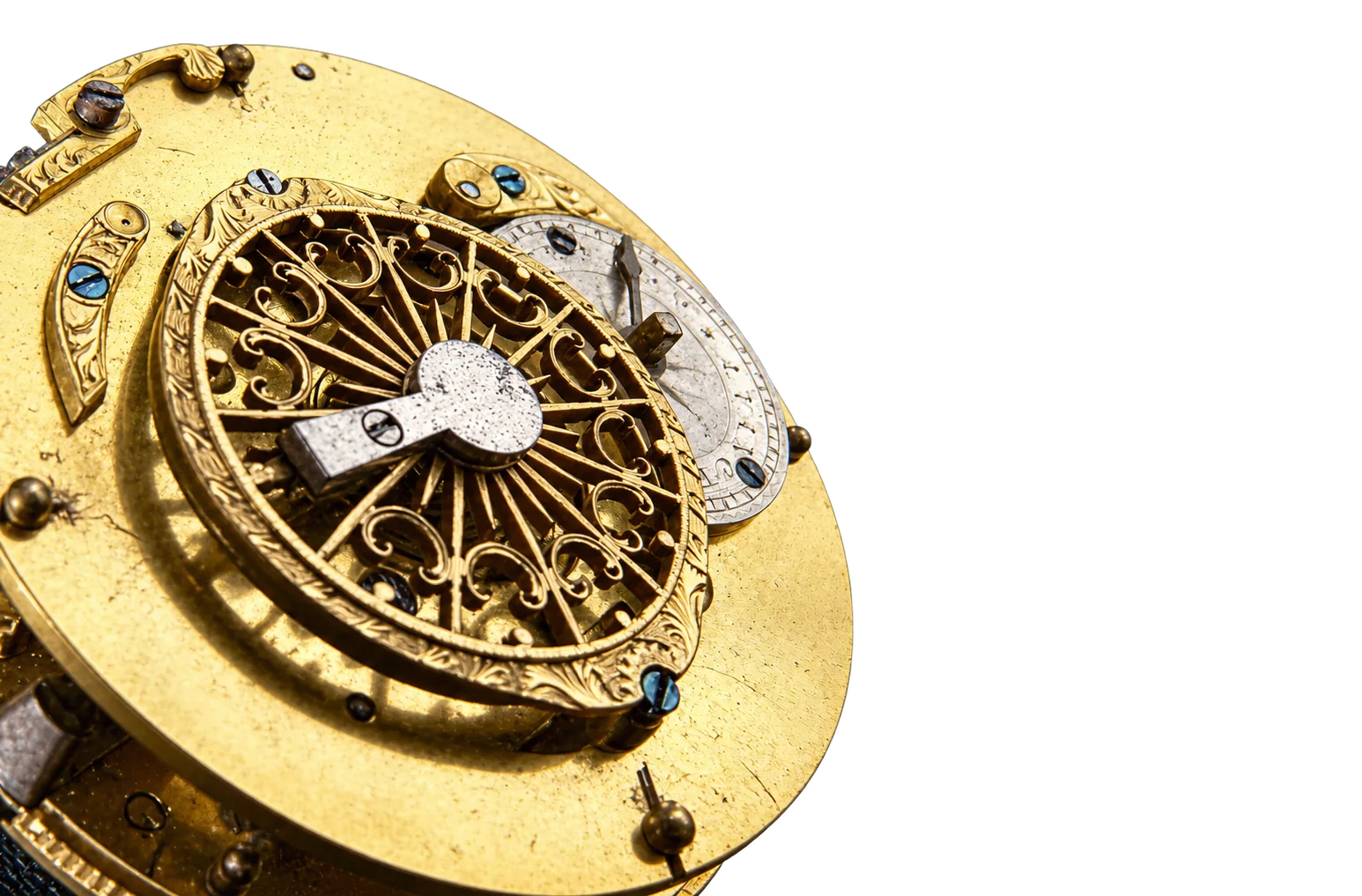 Gros plan sur le mouvement doré d'une montre ancienne dont le coq ajouré et finement gravé est posé sur un fond noir.